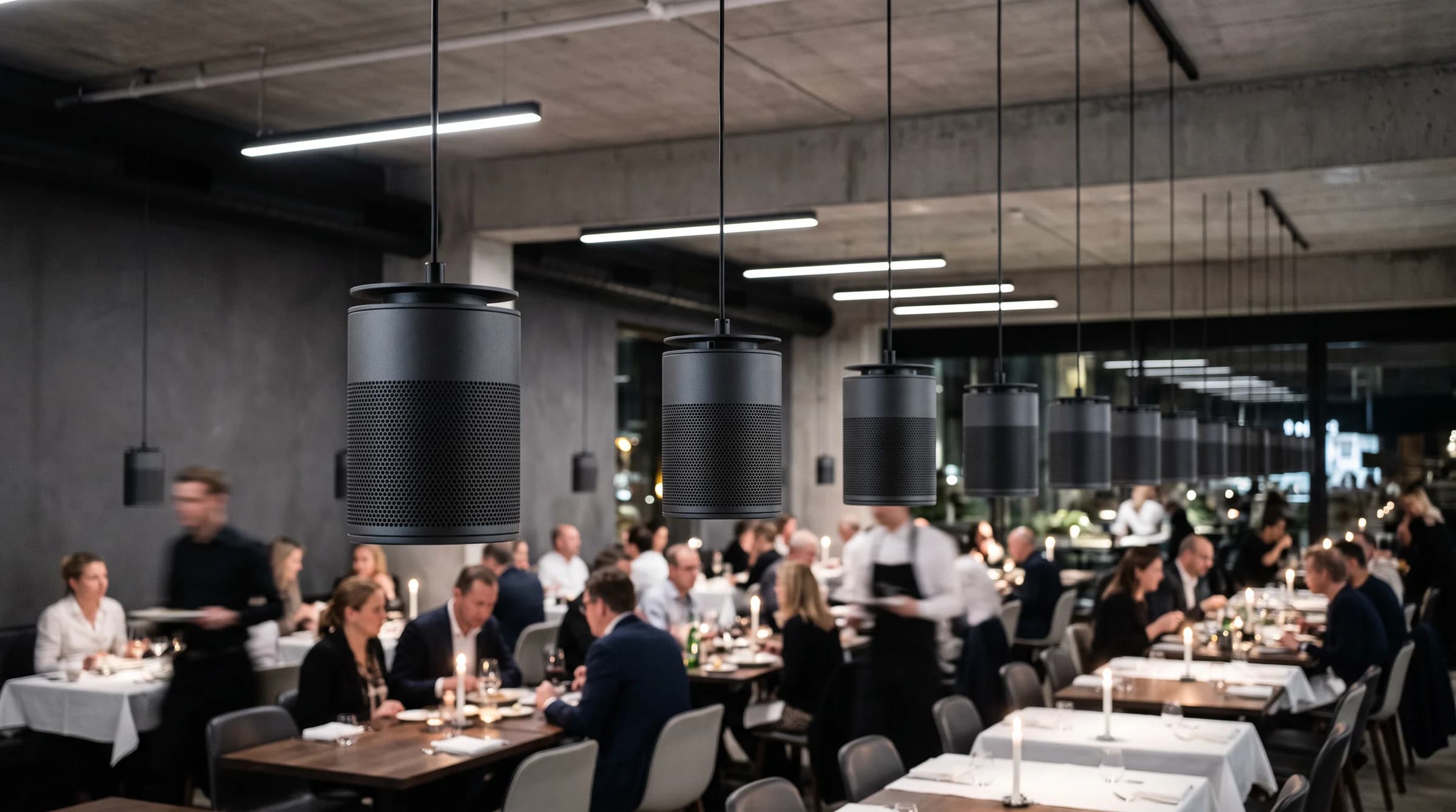 Restaurante contemporáneo de noche con bocinas colgantes sobre las mesas
